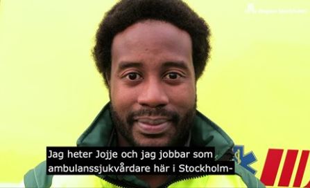 En man ambulanssjukvårdare står framför en ambulans i arbetskläder