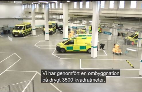 Rymligt stort garage för ambulanser där två män samtalar