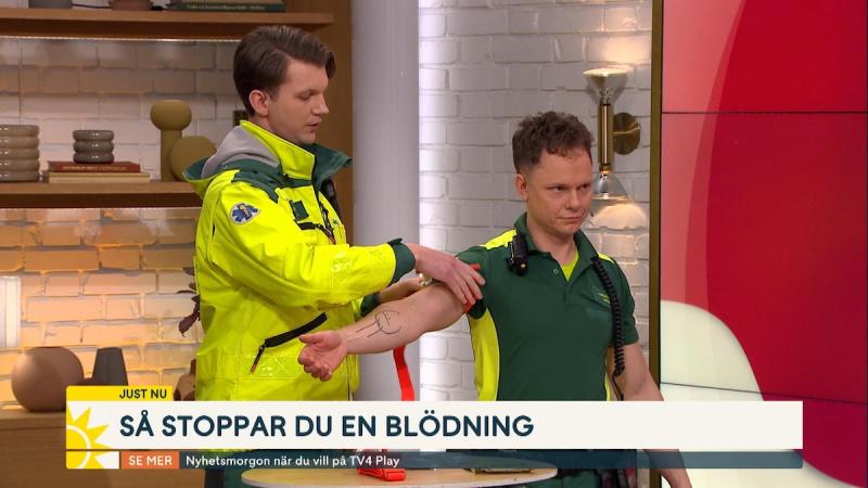 Ambulanspersonal visar hur man kan stoppa en blödning med en tourniquet, förband.